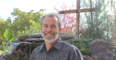 Pastor Mike McClure stands in front of a cross