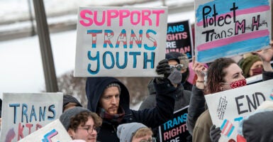 Protesters hold signs reading 