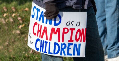 Parent holds protest sign at school protest.