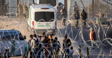 Border Patrol are seen with their white vans as a group of illegal aliens are gathered after crossing the border.