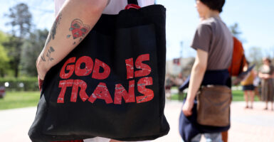 Activist holds bag reading, "God is trans"