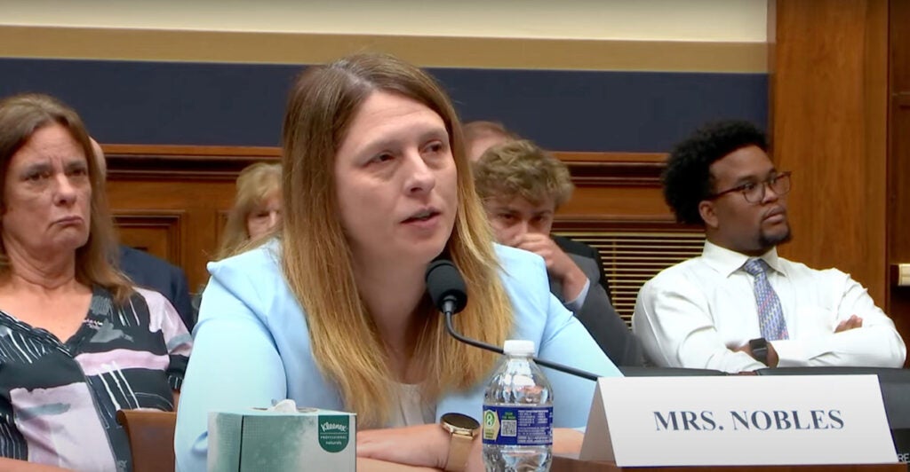 Mother Tammy Nobles speaks into a microphone wearing a blue blazer.