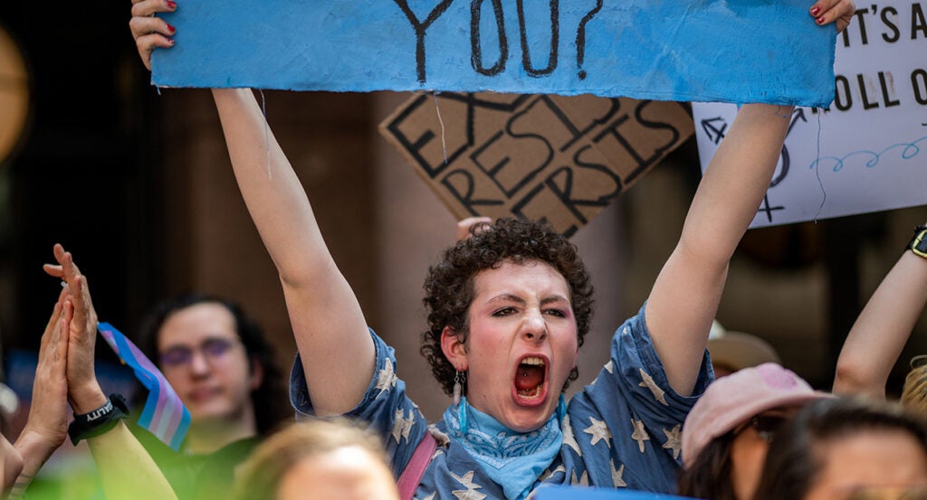 Female pro-transgender protester screams while holding sign