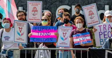 Pro-transgender activists protest with signs reading 