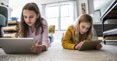 two young girls using digital tablets