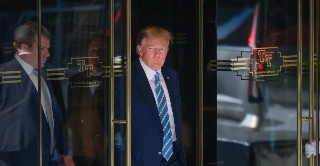 Donald Trump opens a door in a suit