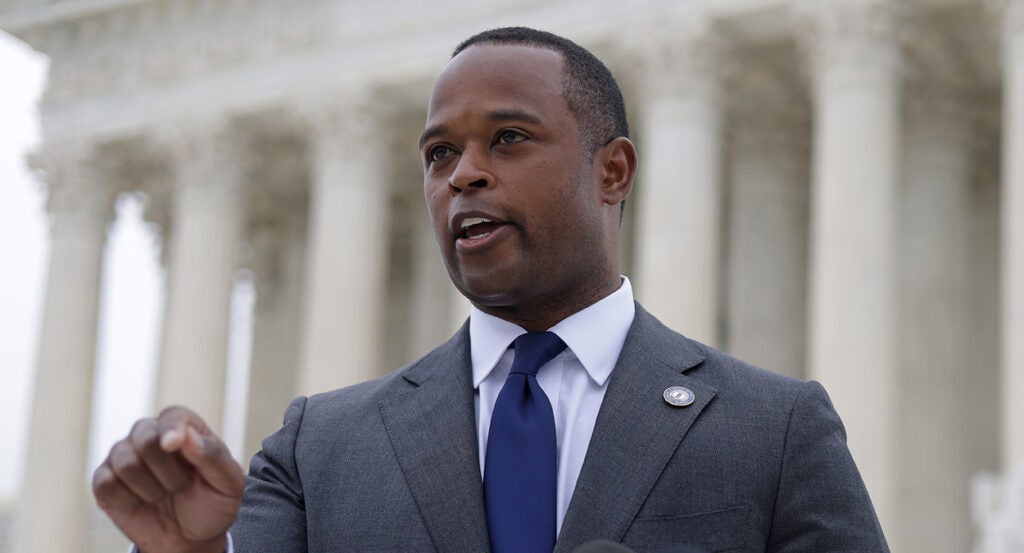 Daniel Cameron in a grey suit with a blue ti in front of the Supreme Court