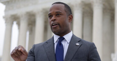 Daniel Cameron in a grey suit with a blue ti in front of the Supreme Court