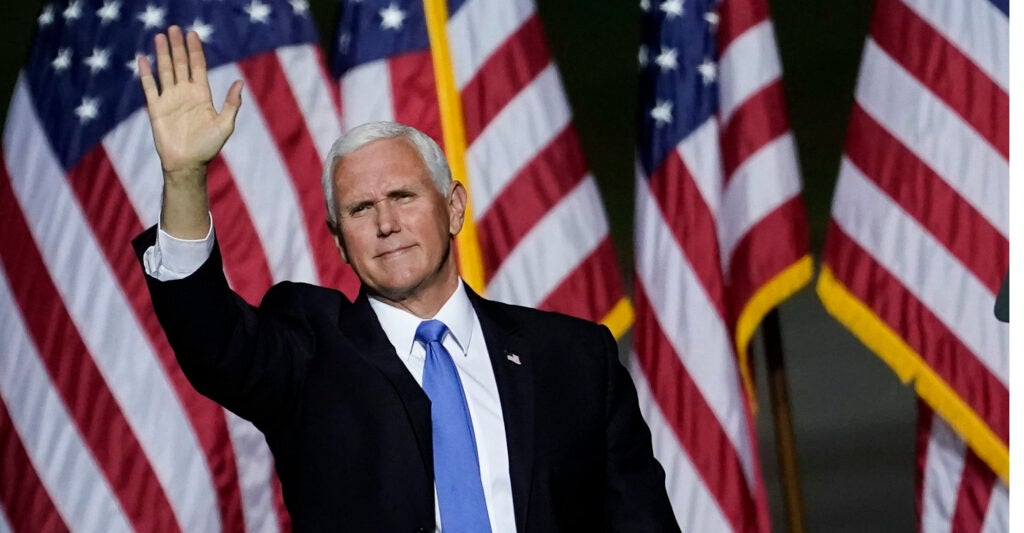 Former Vice President Mike Pence waves in front of American flags