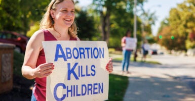 A woman holds a sign reading, 