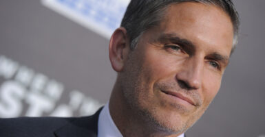 Jim Caviezel smiles in a suit