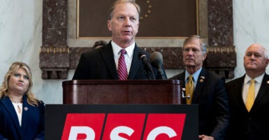 Rep. Kevin Hern speaks into a microphone at a podium with a few members of Congress standing behind him.