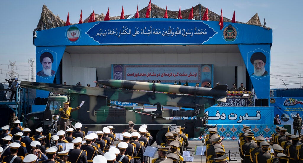 A military vehicle carrying an Iranian surface-to-surface missile past portraits of Supreme Leader Ayatollah Ali Khamenei