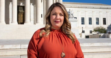 Lorie Smith in a red dress standing in front of the Supreme Court