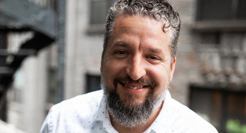 Luke Moon in a salt-and-pepper beard wearing a white dress shirt