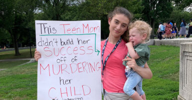 Kaylee Stockton holds baby and sign