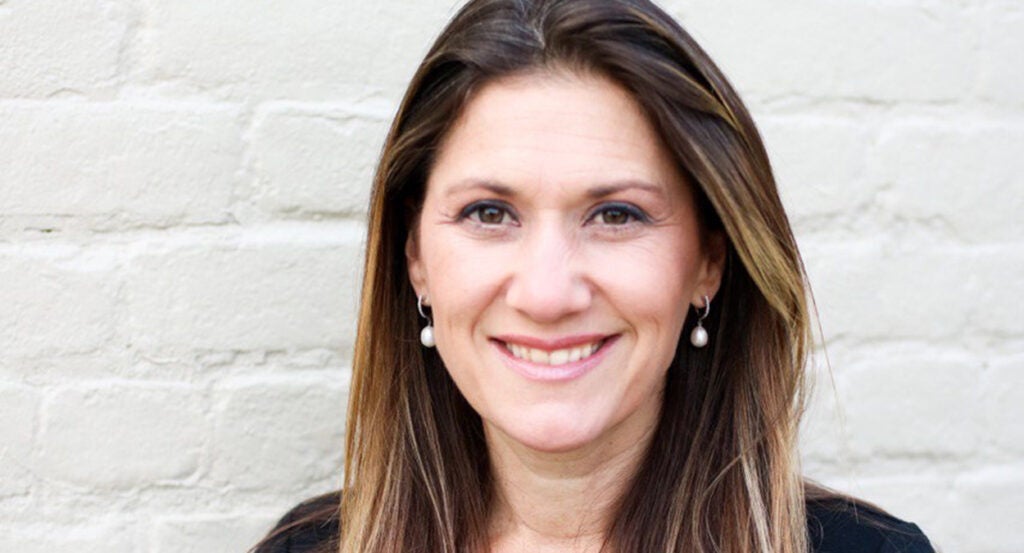 Tina Ramirez smiling in front of a brick wall