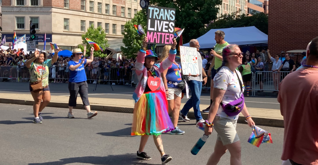 People walk wearing rainbow-clothes in Pride parade.