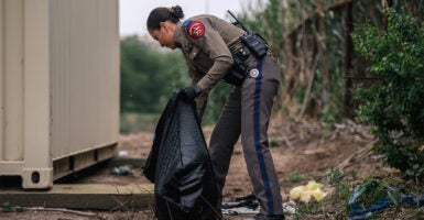 Texas Highway Patrol officer cleans up trash at a border crossing