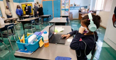 Second-grade student completes online study while sitting