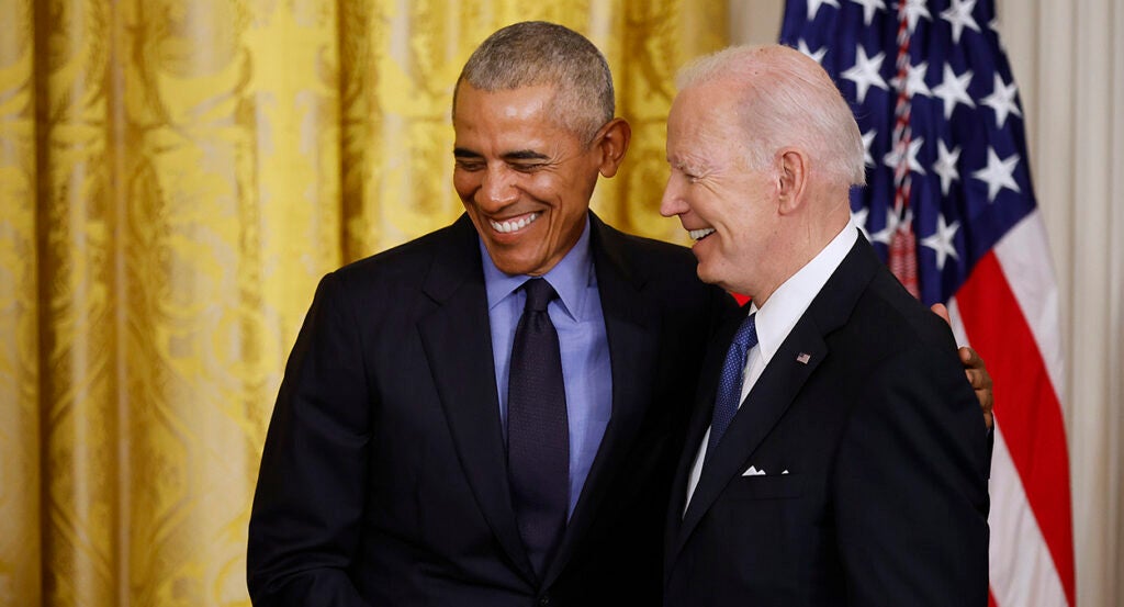 Barack Obama and Joe Biden smiling together in suits