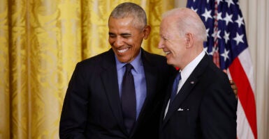 Barack Obama and Joe Biden smiling together in suits