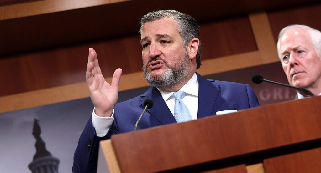 Ted Cruz in a blue suit speaks at a podium