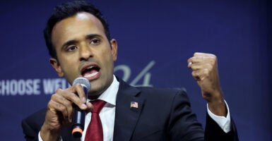 Vivek Ramaswamy speaks into a microphone with his hand in the air.