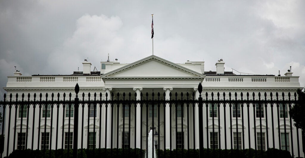 A large black iron fence runs in front of the White House.