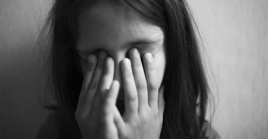 Little girl covers her face with hands