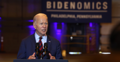 Joe Biden stands in front of a sign reading Bidenomics