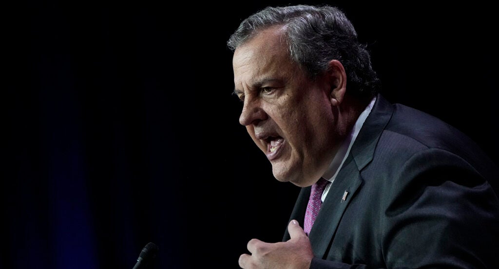 Chris Christie gestures while wearing a suit