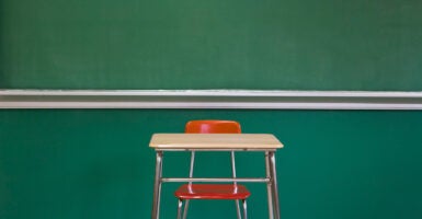 A single desk sits in front of a chalkboard.