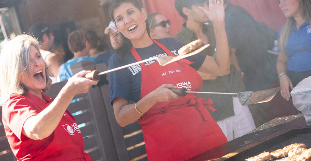 Former South Carolina Gov. and 2024 Republican presidential hopeful Nikki Haley and Sen. Joni Ernst, R-Iowa, flip burgers at the Iowa State Fair wearing red aprons.