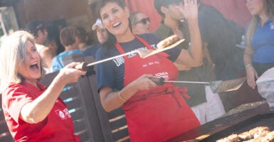 Former South Carolina Gov. and 2024 Republican presidential hopeful Nikki Haley and Sen. Joni Ernst, R-Iowa, flip burgers at the Iowa State Fair wearing red aprons.