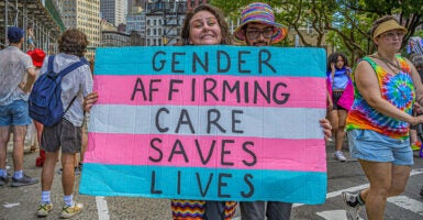 Woman holds transgender flag sign reading 