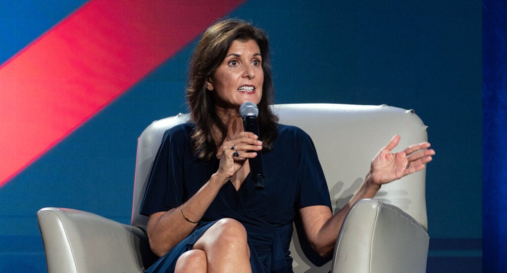 Nikki Haley sits while holding a microphone