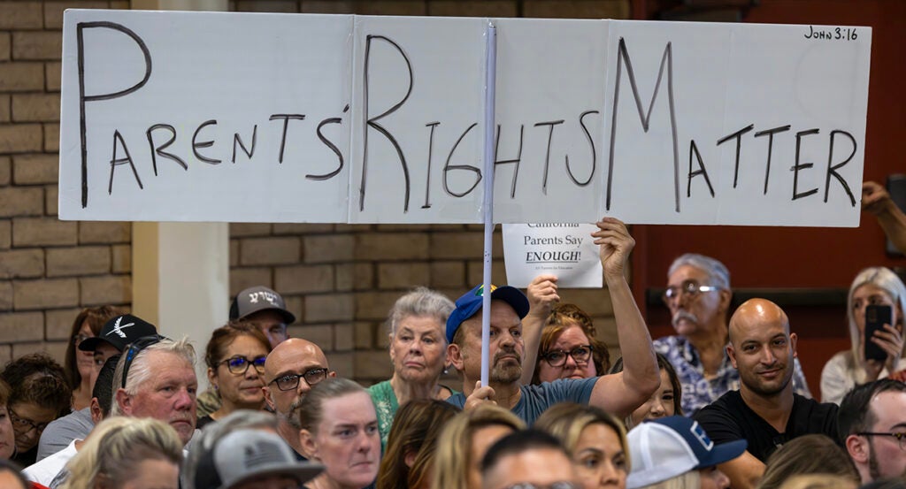 Man holds sign reading "Parents' Rights Matter" at school board meeting