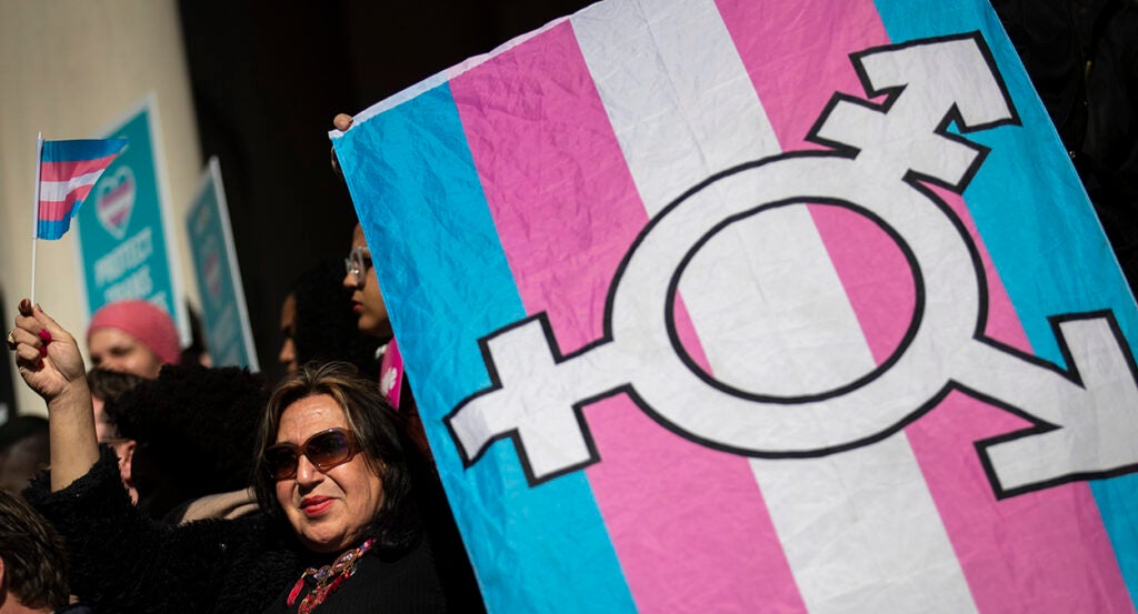 Woman holds transgender flag with transgender symbol