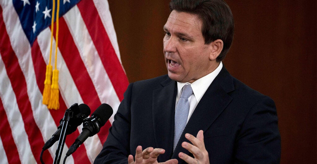 Ron DeSantis speaks from podium with American flag in the background