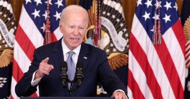 President Joe Biden speaking from podium, looking angry with US flags in background