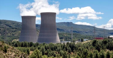 Two nuclear power plant chimneys between mountains and forests.