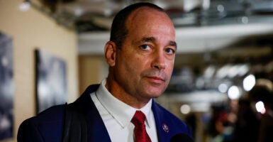 Rep. Bob Good glances at the camera wearing a black jacket and a red tie