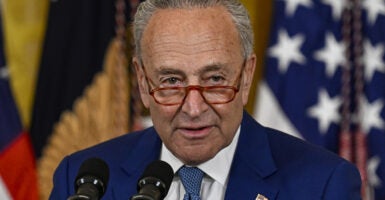 Chuck Schumer in a blue suit in front of an American flag