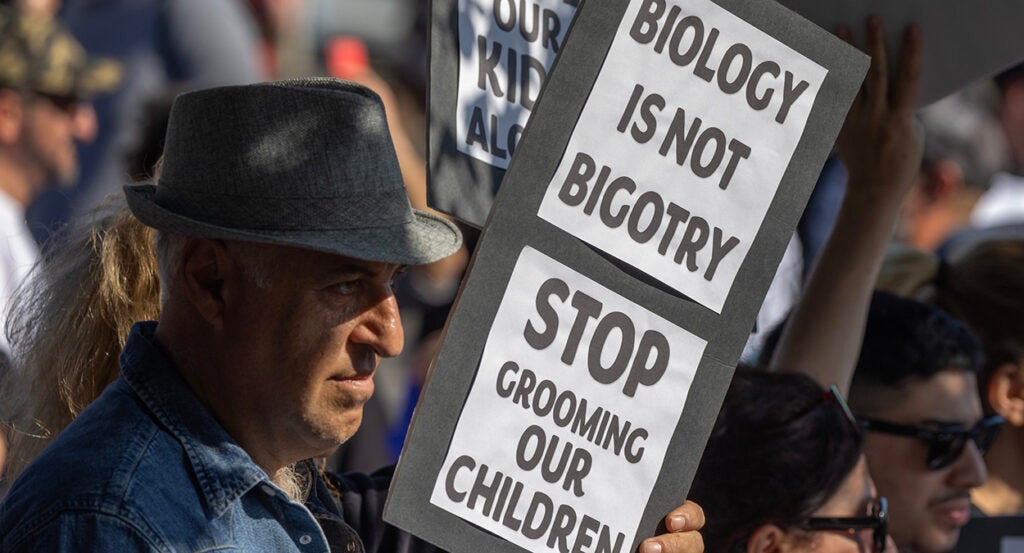 A man holds a sign reading "biology is not bigotry"