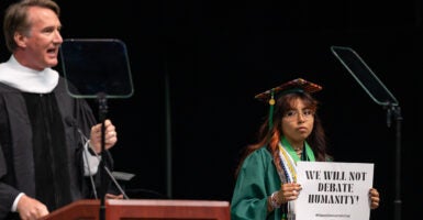 George Mason University graduate holds a sign reading 