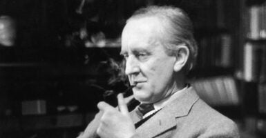 JRR Tolkien smokes a pipe in a suit as he sits in front of a bookcase