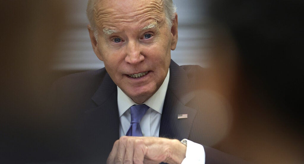 President Joe Biden gestures in a suit with an American flag pin