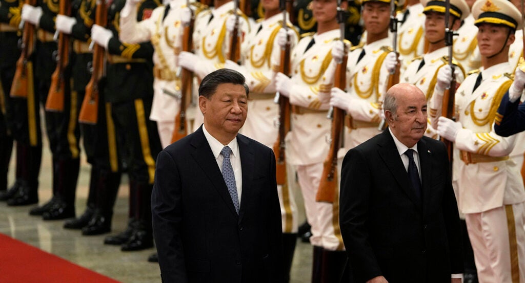 Chinese President Xi Jinping, wearing a suit, walks in front of Chinese soldiers