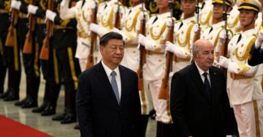 Chinese President Xi Jinping, wearing a suit, walks in front of Chinese soldiers